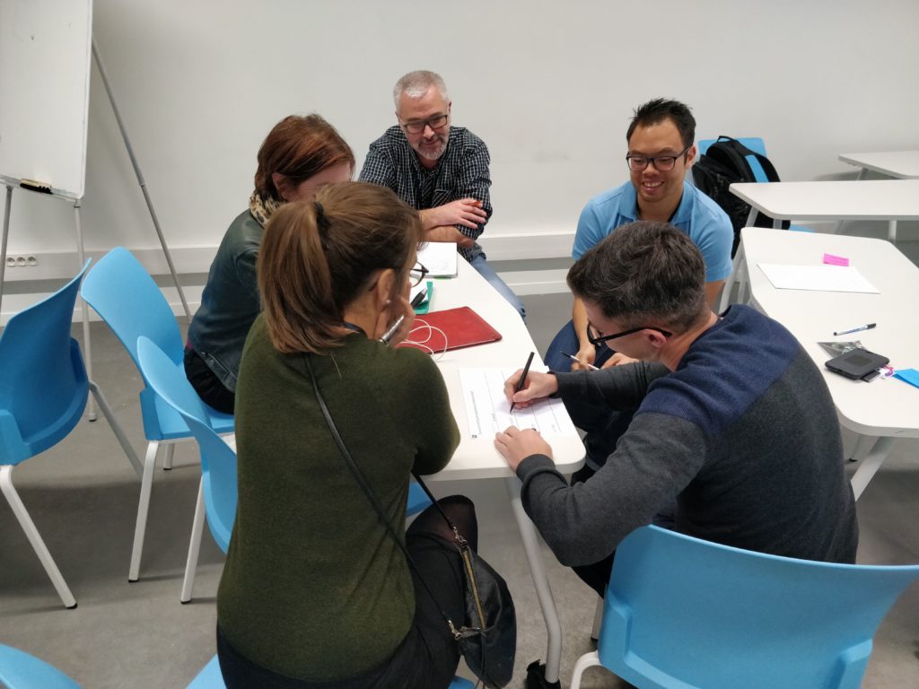 Groupe de personnes autour d'une table, en train d'écrire, en pleine réfléxion - UXcamp 2018