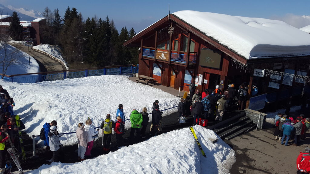 une longue file d'attente aux caisses des forfaits d'une station de ski, point de contact clé du parcours utilisateur